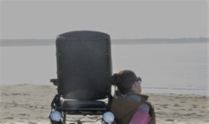 Wheelymum sitzt neben ihrem Rollstuhl am Strand